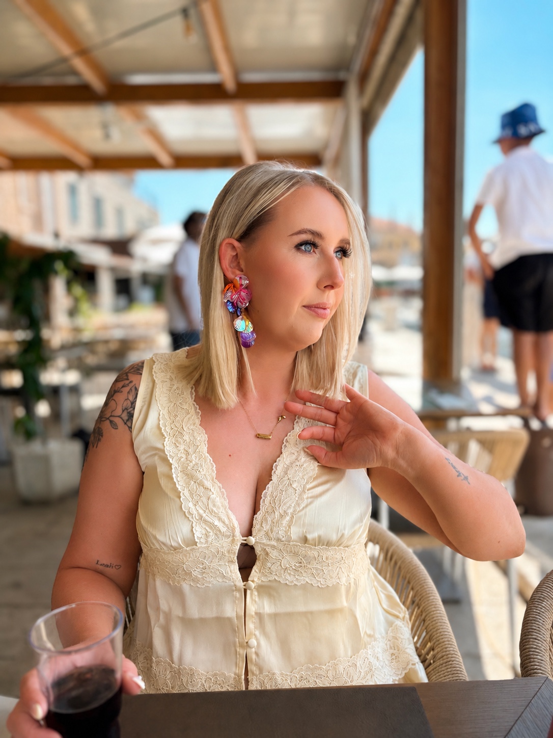 Rebecca in a cream outfit wearing colourful statement earrings